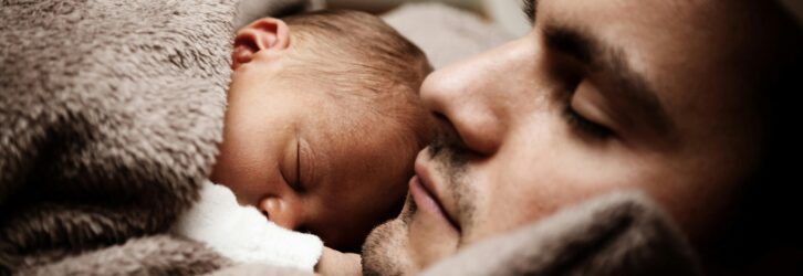 A touching close-up of a father and his baby peacefully napping together.